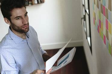 Young businessman working in office, holding documents - GIOF03280