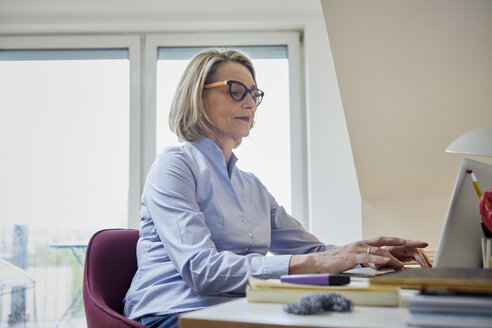 Mature woman at home using laptop at desk - RBF06029