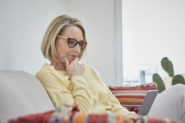 Mature woman at home looking at cell phone on the sofa - RBF06042