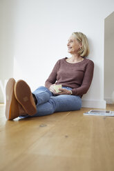 Smiling mature woman at home sitting on the floor - RBF06049