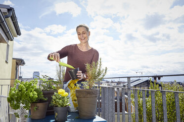 Smiling mature woman caring for plants on balcony - RBF06053