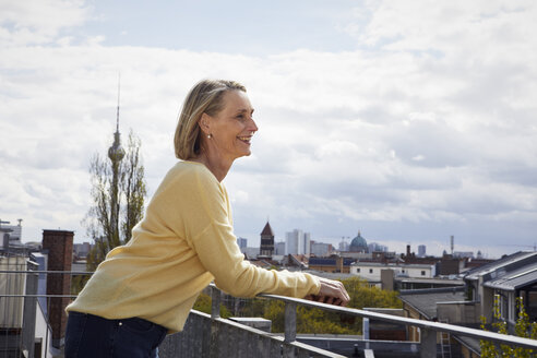 Lächelnde reife Frau auf Balkon mit Blick auf die Aussicht - RBF06055