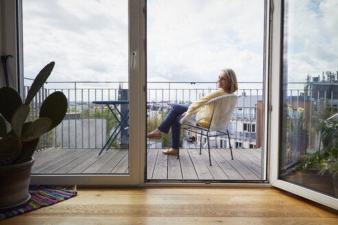 Lächelnde reife Frau zu Hause auf dem Balkon sitzend - RBF06057