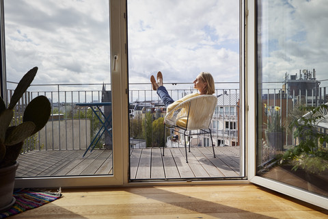 Reife Frau zu Hause entspannt auf dem Balkon, lizenzfreies Stockfoto