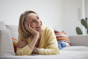 Lächelnde reife Frau zu Hause auf dem Sofa träumend - RBF06061