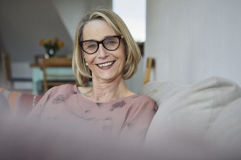 Porträt einer lächelnden reifen Frau zu Hause auf dem Sofa - RBF06064