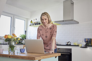 Mature woman at home using laptop in kitchen - RBF06069