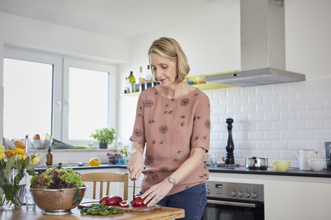 Ältere Frau bereitet einen Salat in der Küche zu, lizenzfreies Stockfoto