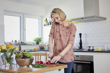 Ältere Frau bereitet einen Salat zu und telefoniert in der Küche - RBF06072