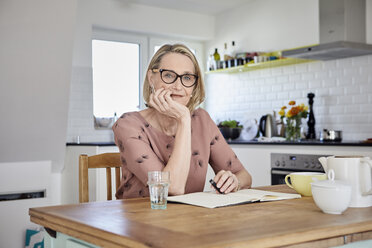 Portrait of mature woman with notebook at kitchen table - RBF06073