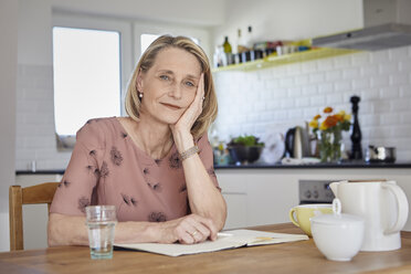 Porträt einer reifen Frau mit Notizbuch am Küchentisch - RBF06074