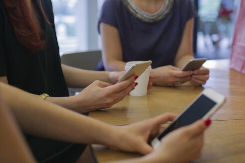 Freundinnen beim Einkaufsbummel, die sich in einem Café treffen und Smartphones benutzen - MOMF00242