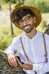 Portrait of smiling man wearing old-fashioned clothes holding cell phone - MGIF00138