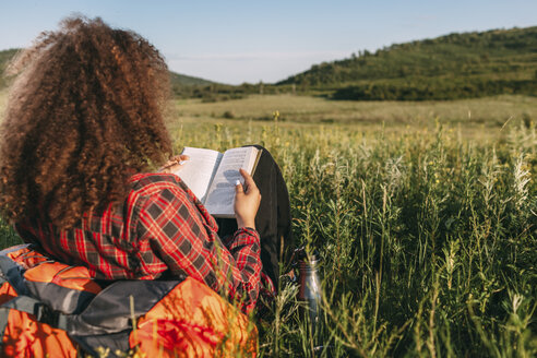 Rückenansicht eines jugendlichen Mädchens, das auf einer Wiese ein Buch liest - VPIF00110