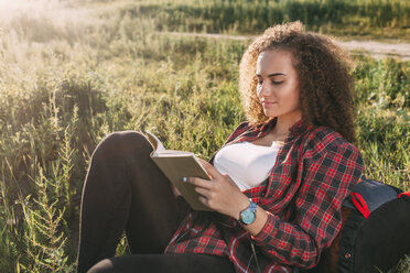 Teenage girl reading book on a meadow - VPIF00111