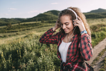 Teenager-Mädchen hört Musik mit Kopfhörern in der Natur - VPIF00113