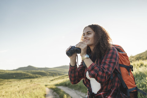 Teenager-Mädchen mit Rucksack und Fernglas in der Natur, lizenzfreies Stockfoto