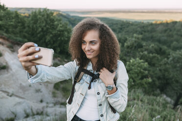 Lächelndes Teenager-Mädchen nimmt Selfie in der Natur - VPIF00136