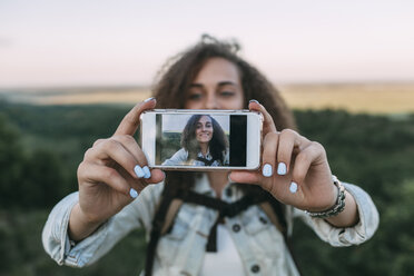 Lächelndes Teenager-Mädchen nimmt Selfie in der Natur - VPIF00137