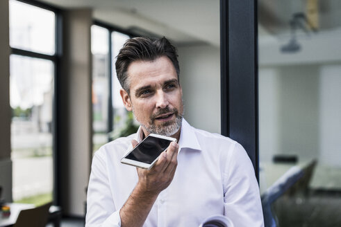 Geschäftsmann benutzt Mobiltelefon im Büro - UUF11678