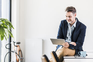 Businessman holding tablet in office - UUF11721