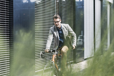 Shocked businessman on bicycle looking at cell phone - UUF11727