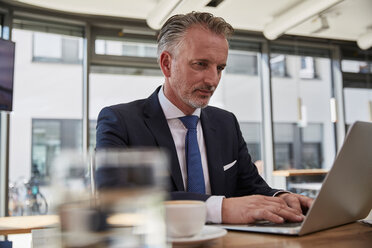 Geschäftsmann, der auf dem Flughafen wartet und einen Laptop benutzt - SUF00308