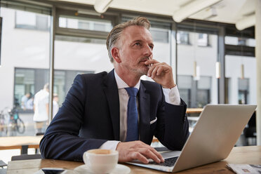 Businessman waiting at the airport, using laptop - SUF00309