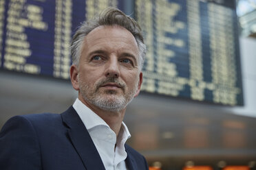 Businessman at the airport in front of arrival and departure board - SUF00335