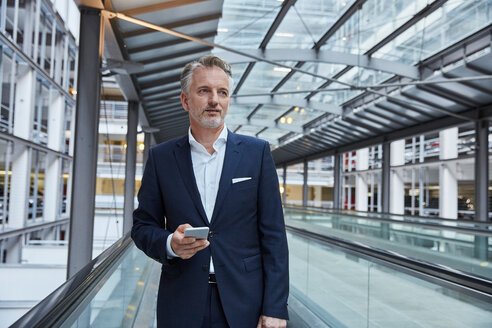 Geschäftsmann mit Smartphone auf dem Flughafen, stehend auf dem Fahrsteig - SUF00336