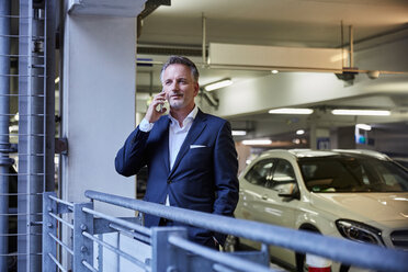 Businessman using smartphone in parking garage - SUF00339