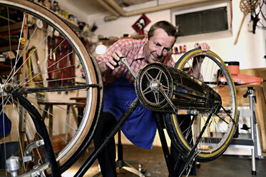 Älterer Mann überprüft Fahrrad in seiner Werkstatt - ECPF00128