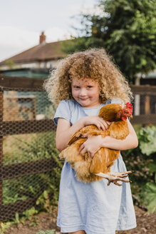 Lächelndes Mädchen, das eine Henne umarmt - NMSF00155
