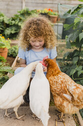 Little girl feeding chickens in allotment - NMSF00159