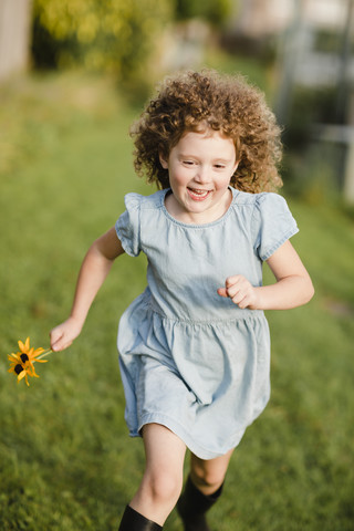 Happy little girl running on a meadow in the garden stock photo