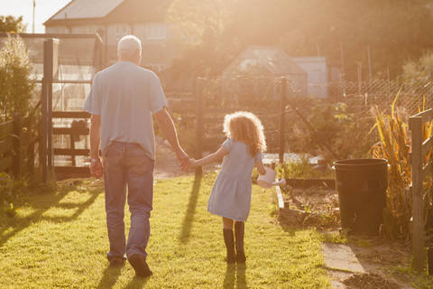 Kleines Mädchen Hand in Hand mit ihrem Onkel im Garten, lizenzfreies Stockfoto