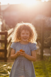 Porträt eines kleinen Mädchens bei Gegenlicht im Garten stehend - NMSF00171