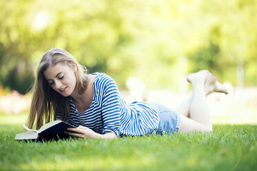 Junge Frau, die ein Buch liest, im Freien - MAEF12432