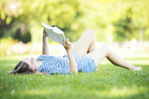 Junge Frau, die ein Buch liest, im Freien - MAEF12434