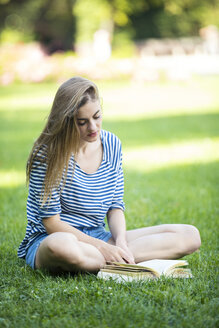 Junge Frau, die ein Buch liest, im Freien - MAEF12435