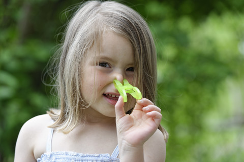 Porträt eines kleinen Mädchens mit Wäscheklammer auf der Nase, lizenzfreies Stockfoto