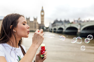 UK, London, woman making soap bubbles near Westminster Bridge - MGOF03628