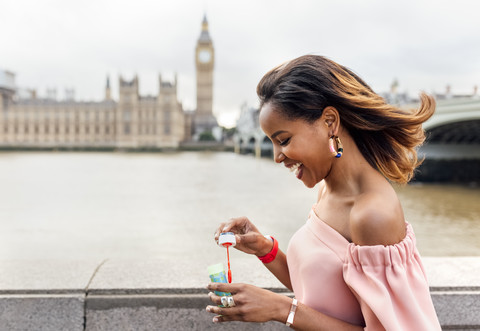 UK, London, glückliche Frau macht Seifenblasen in der Nähe der Westminster Bridge, lizenzfreies Stockfoto
