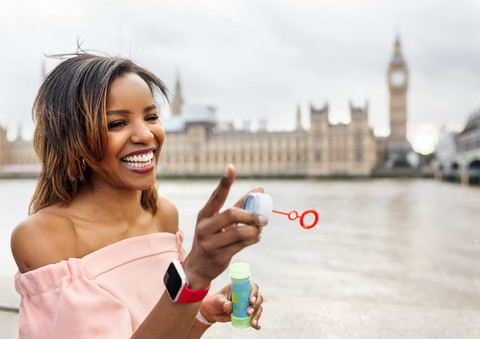 UK, London, happy woman making soap bubbles near Palace of Westminster stock photo