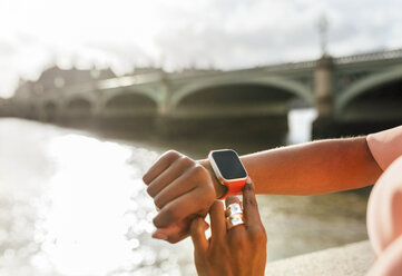UK, London, Nahaufnahme einer Frau, die ihre Smartwatch in der Nähe der Westminster Bridge benutzt - MGOF03637
