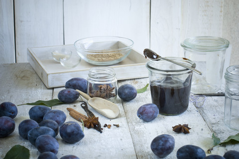 Einmachglas mit Pflaumenmarmelade und Zutaten auf Holz, lizenzfreies Stockfoto