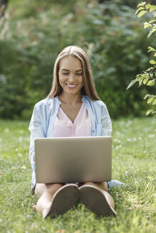 Lächelnde junge Frau mit Laptop auf einer Wiese - VPIF00140
