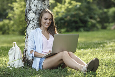 Lächelnde junge Frau mit Laptop auf einer Wiese - VPIF00144