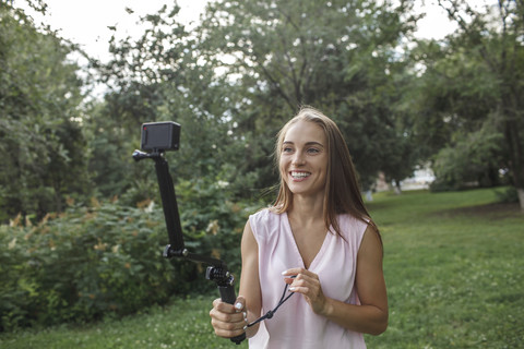 Lächelnde junge Frau, die ein Foto von sich auf einer Wiese macht, lizenzfreies Stockfoto