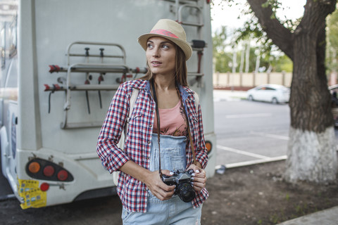 Junge Frau mit einer Kamera auf einem Parkplatz, die sich umschaut, lizenzfreies Stockfoto